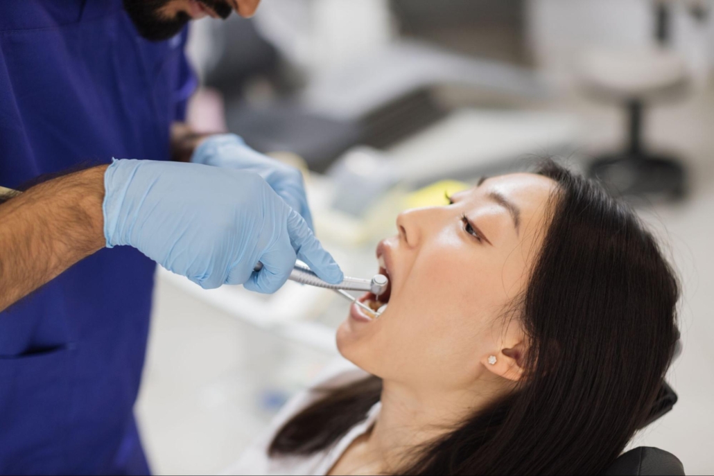 A male dentist is doing a dental checkup on a female patient.