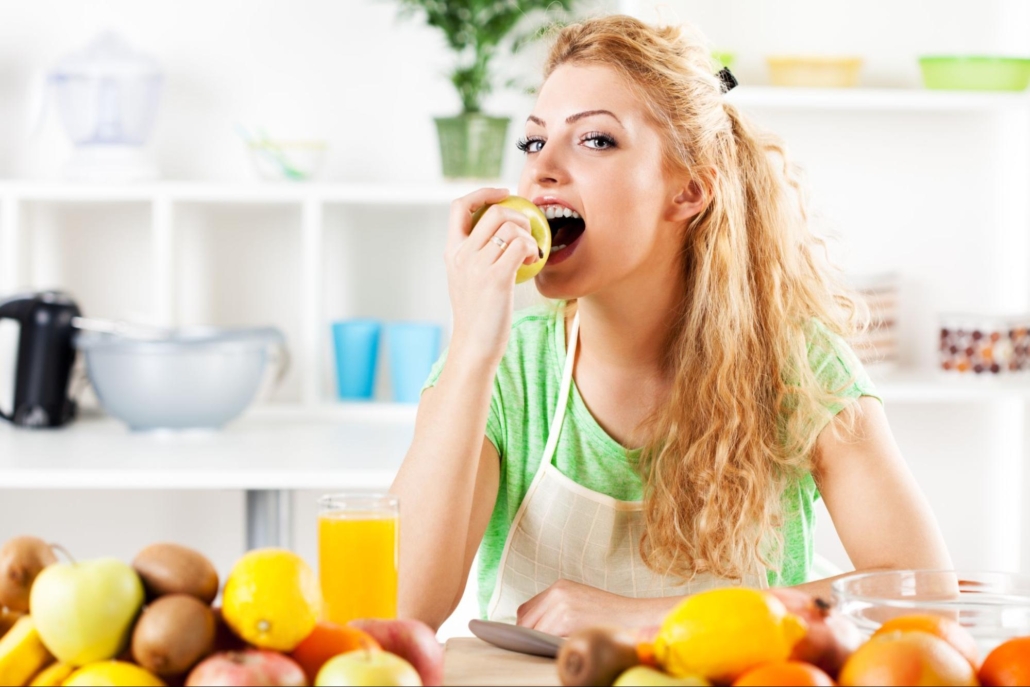 A blonde woman is eating fruits.