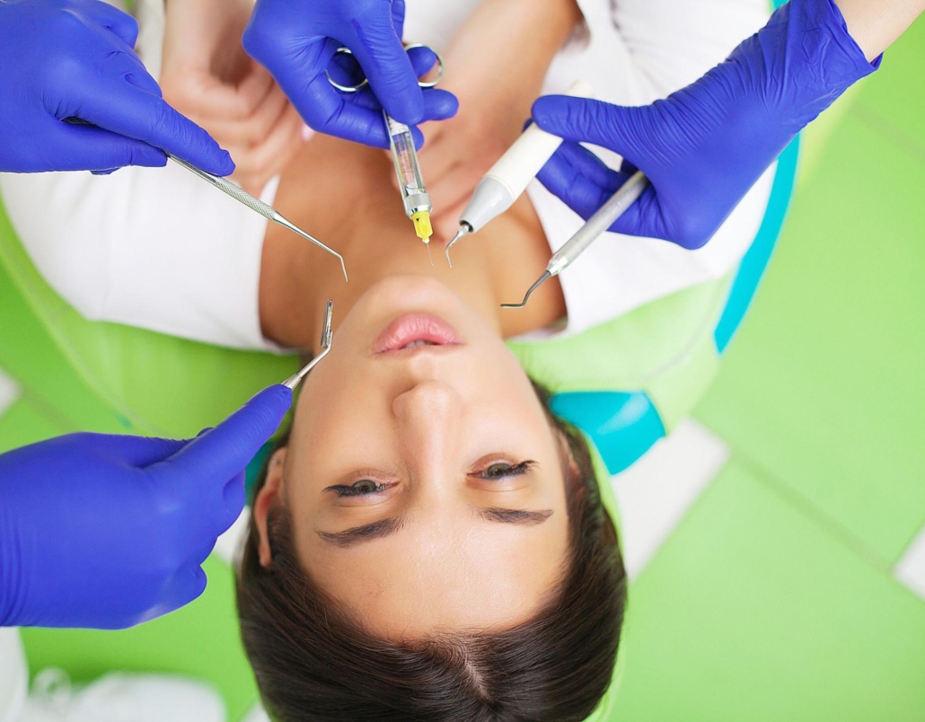 A woman visits her dentist for a teeth examination surrounded by different dental tools.