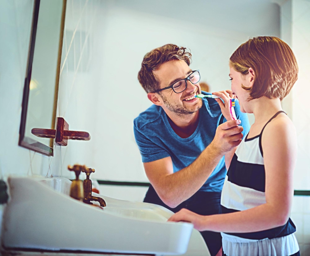 A father and daughter brushing their teeth together.