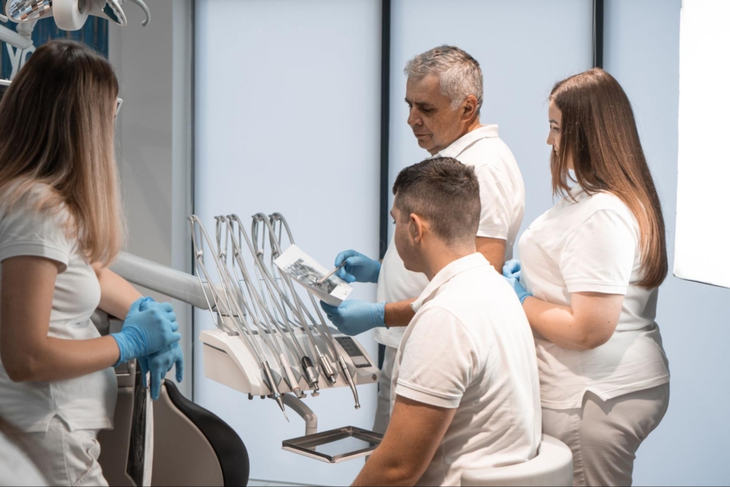 A dentist and staff members conducting a collective examination of X-rays.