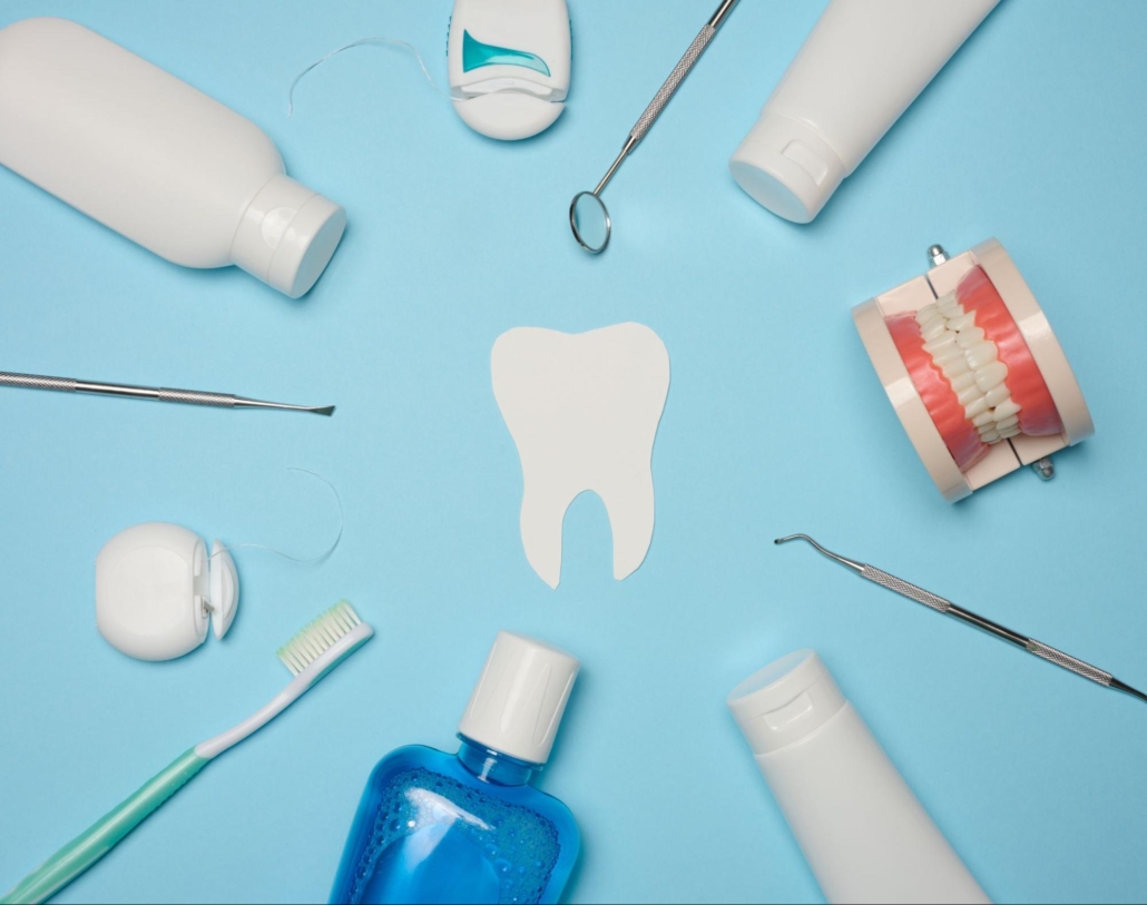 Outline of a tooth next to floss, toothbrushes, dental tools, and a model of teeth. 