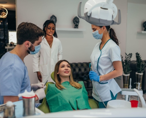 A woman in an exam chair next to three dentists wearing masks.
